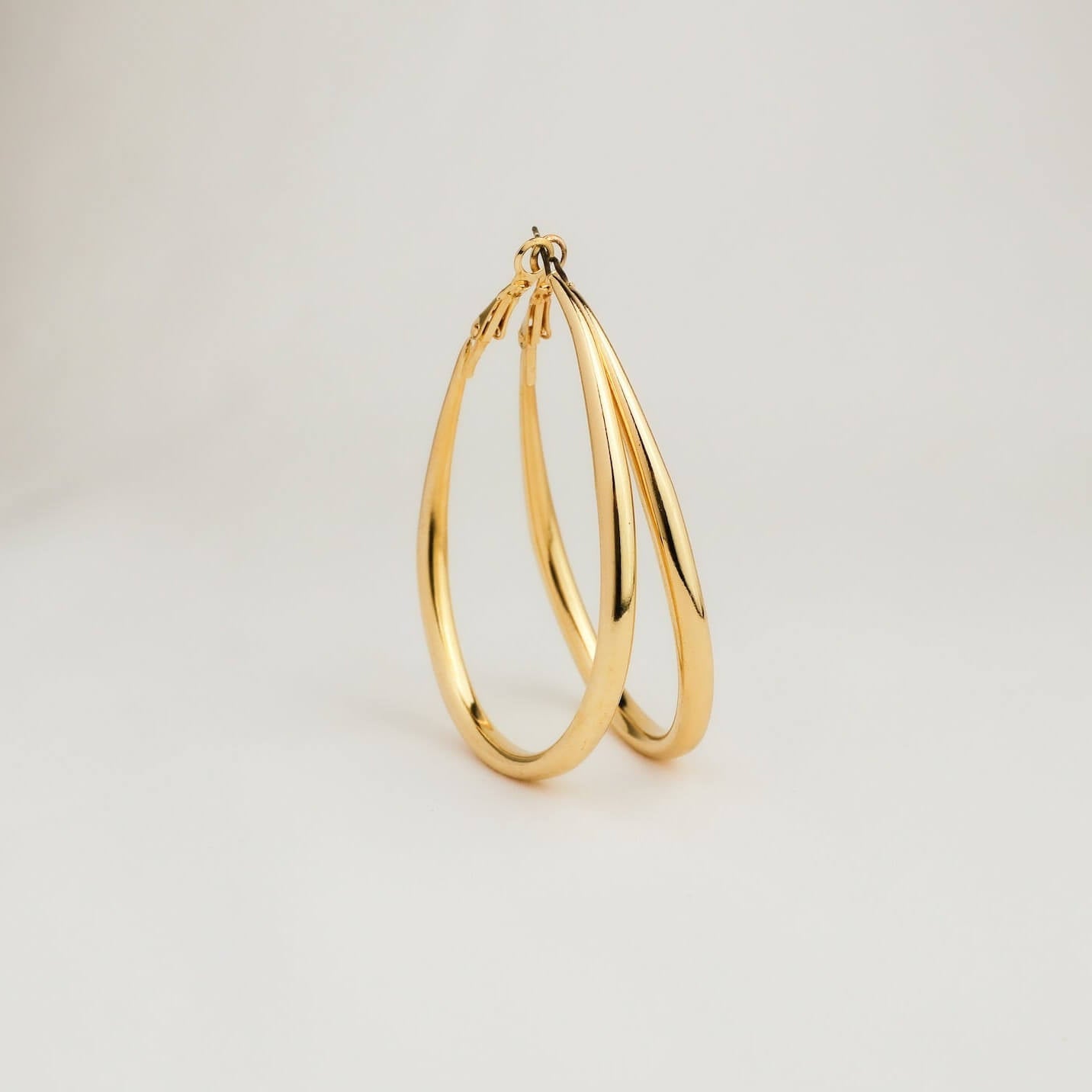 Gold hoop earring on a light gray background