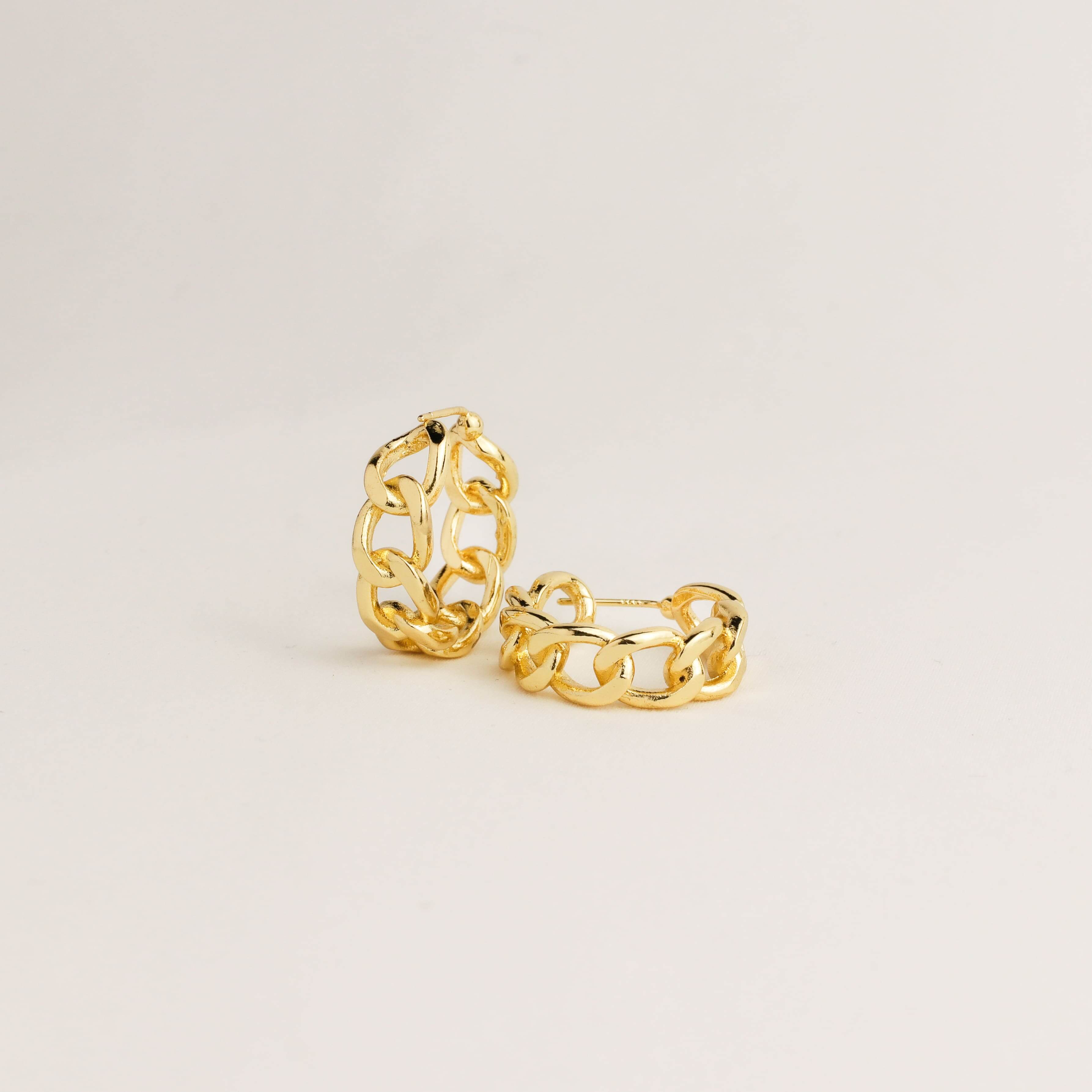 Pair of gold hoop earrings on a light beige background