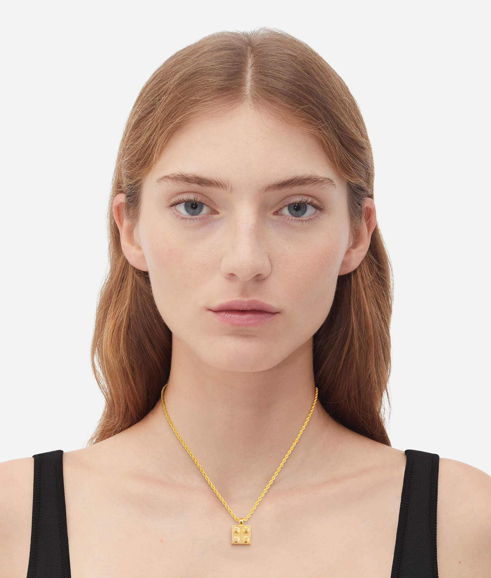 Woman wearing a gold necklace with a pendant on a white background