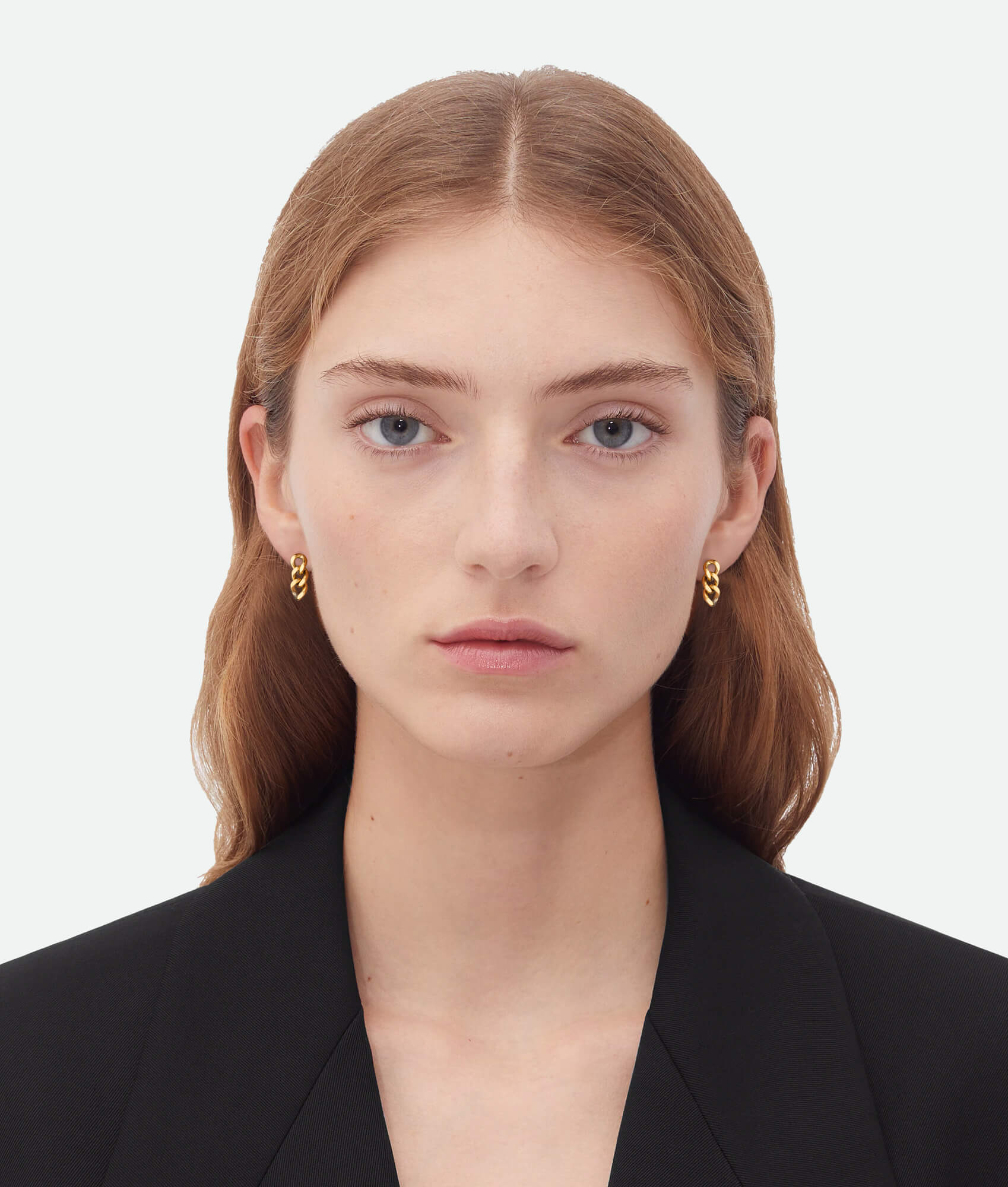 Woman wearing gold hoop earrings against a plain background