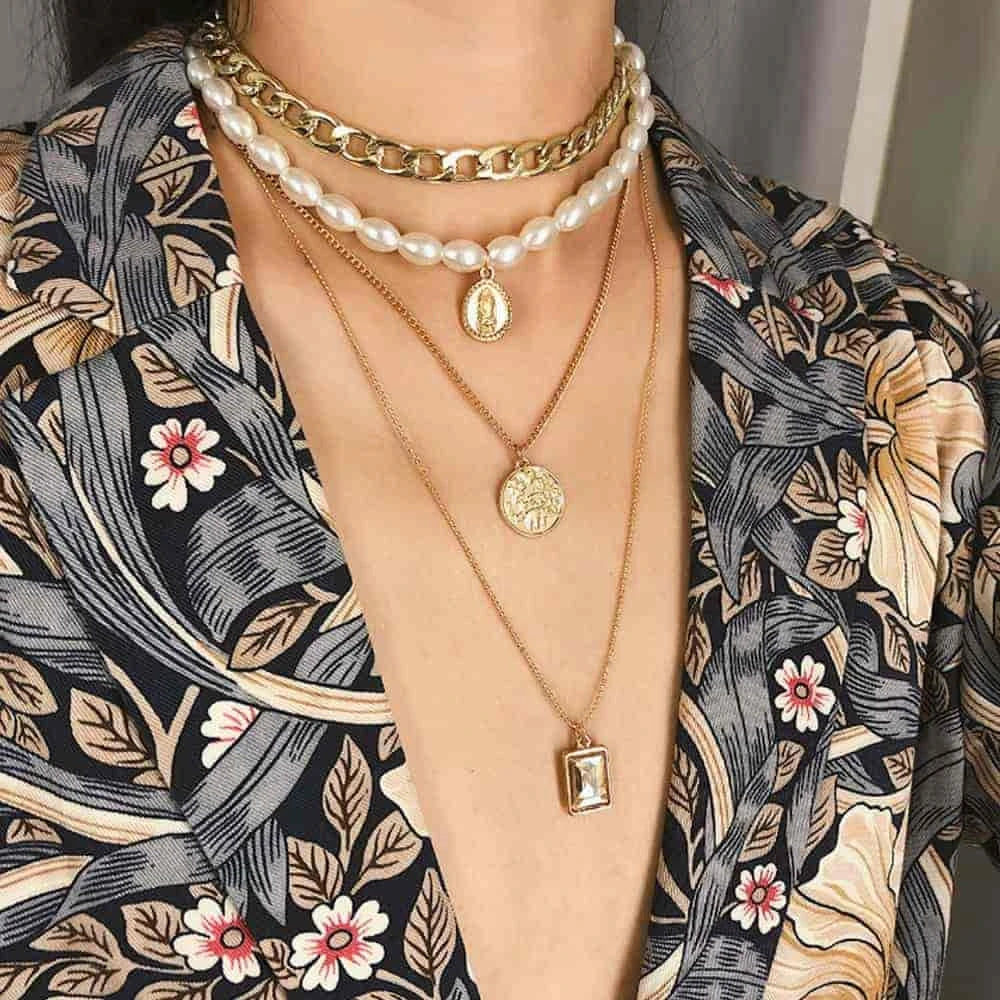 A model wearing gold chain and pearl necklaces