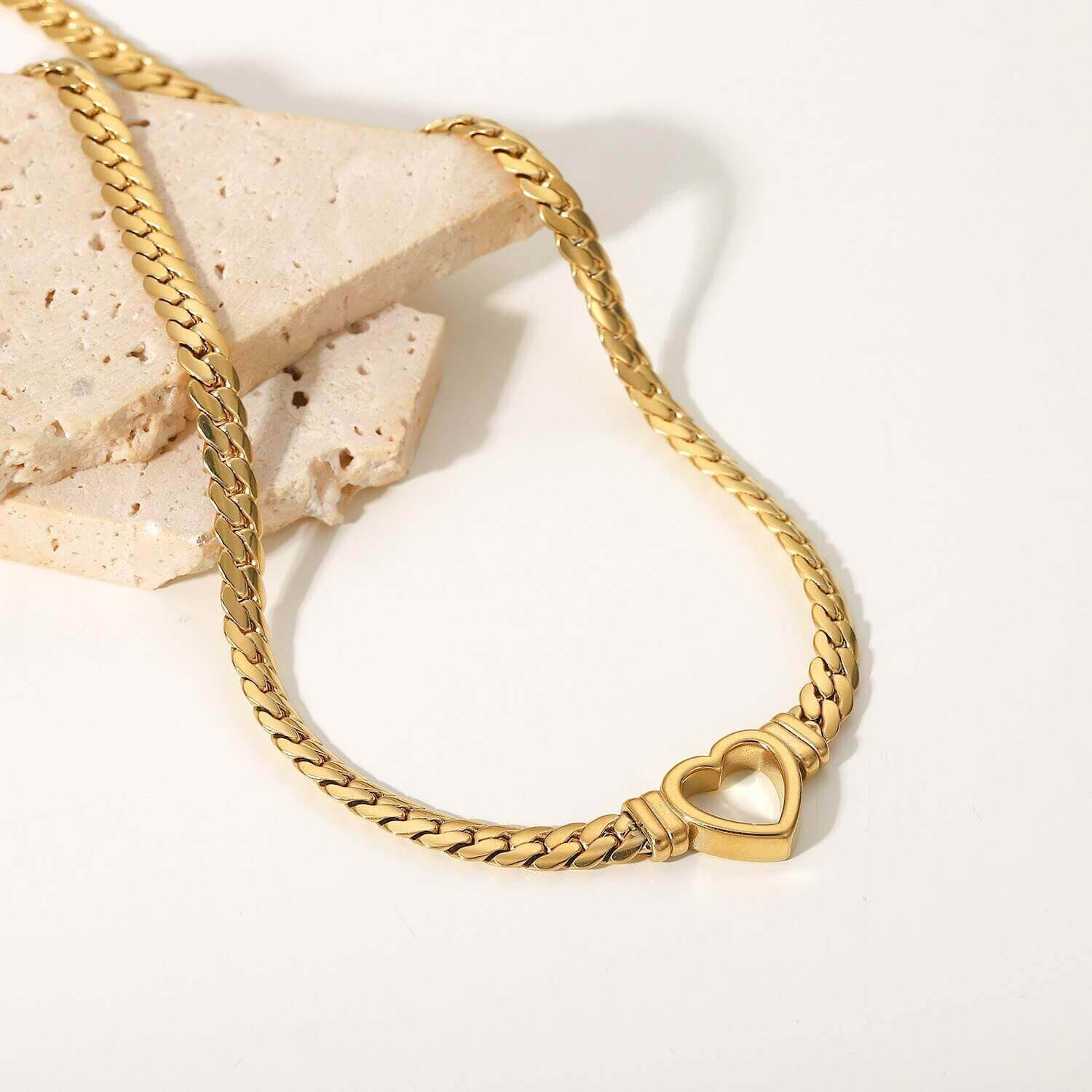 Womens gold necklace draped over a clay tile
