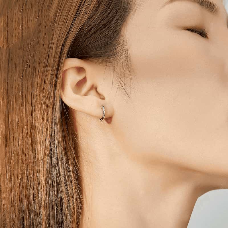 Model wearing silver huggie hoop earrings