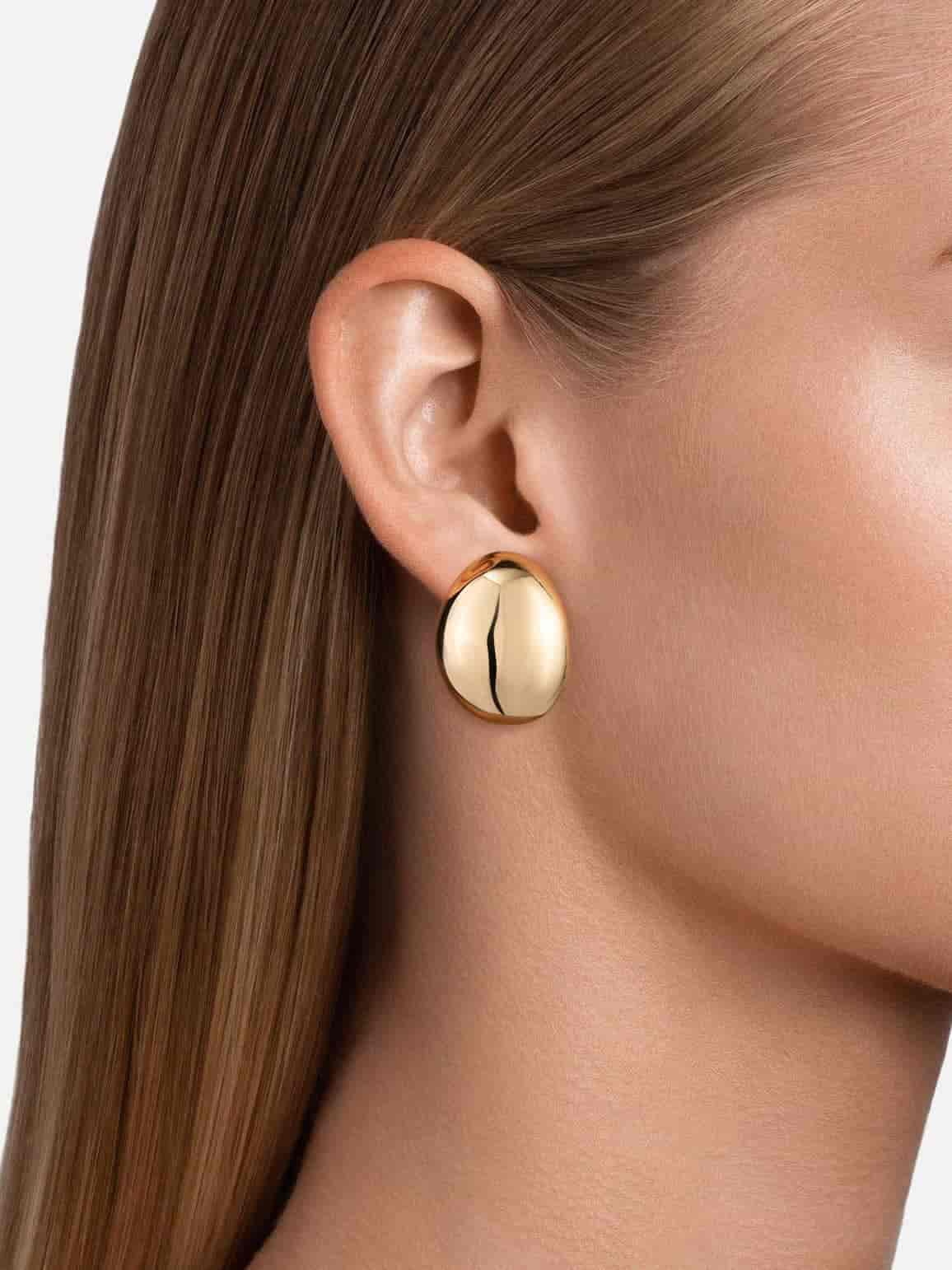 a woman wearing gold shpere earrings