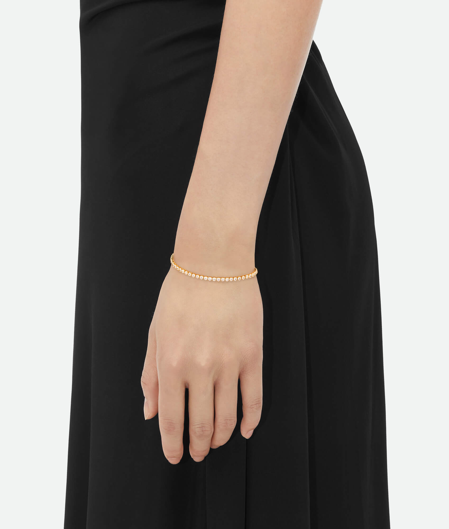 Gold bracelet with clear stones on a white background