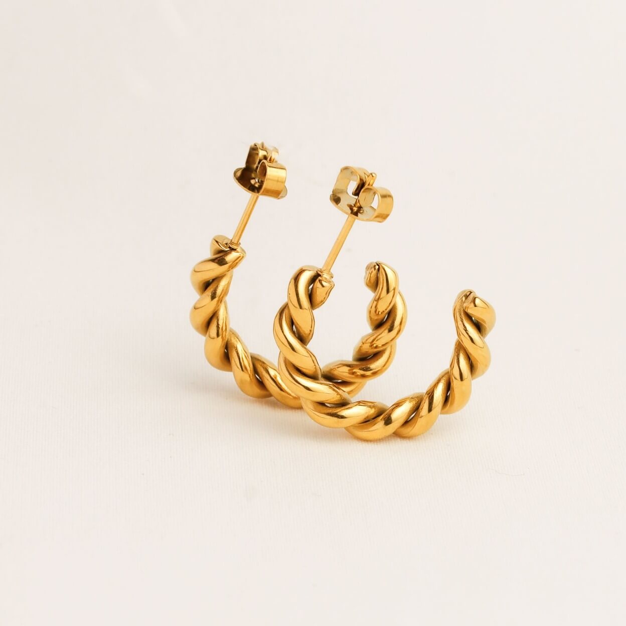 Gold hoop earrings on a light beige background
