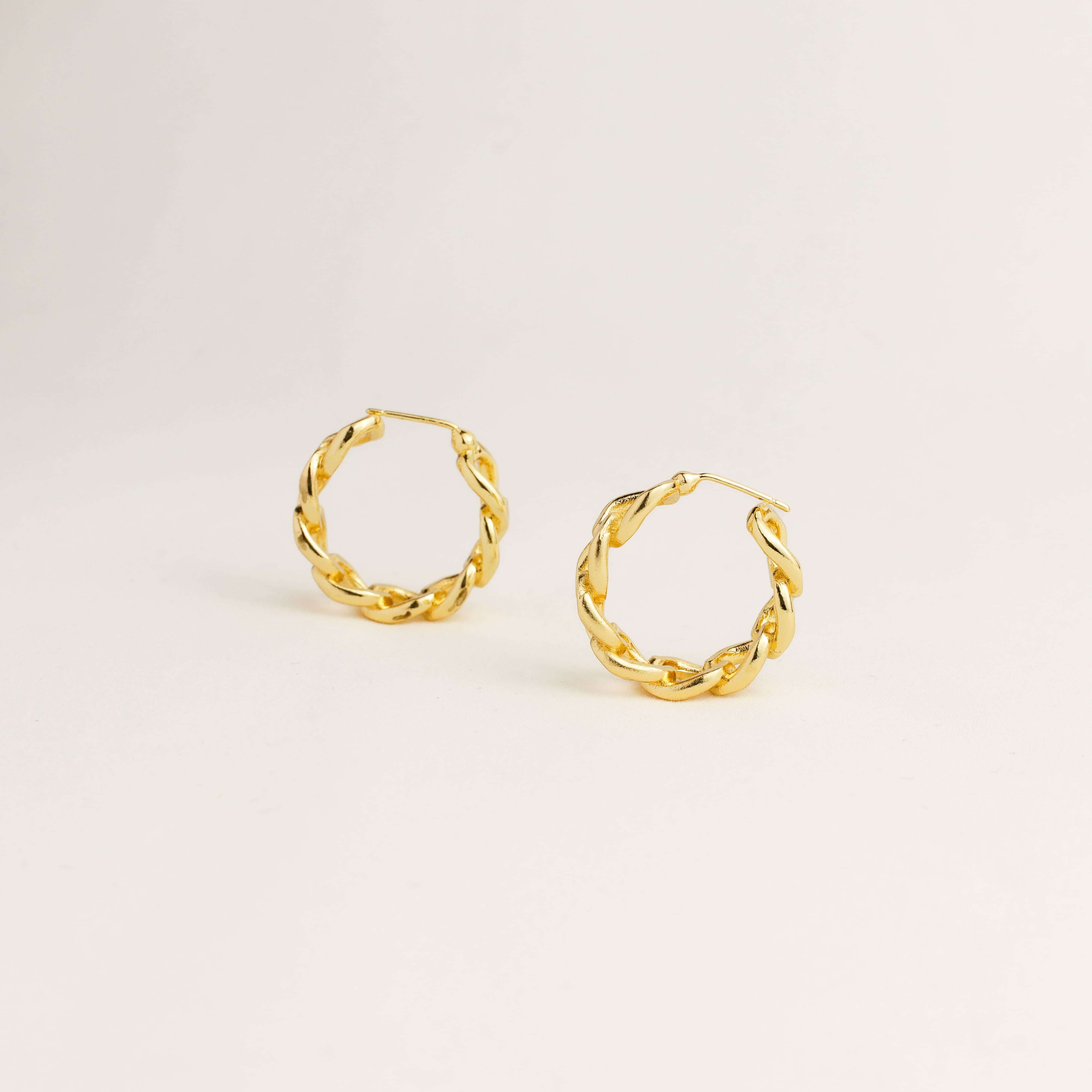 Gold hoop earrings on a light beige background