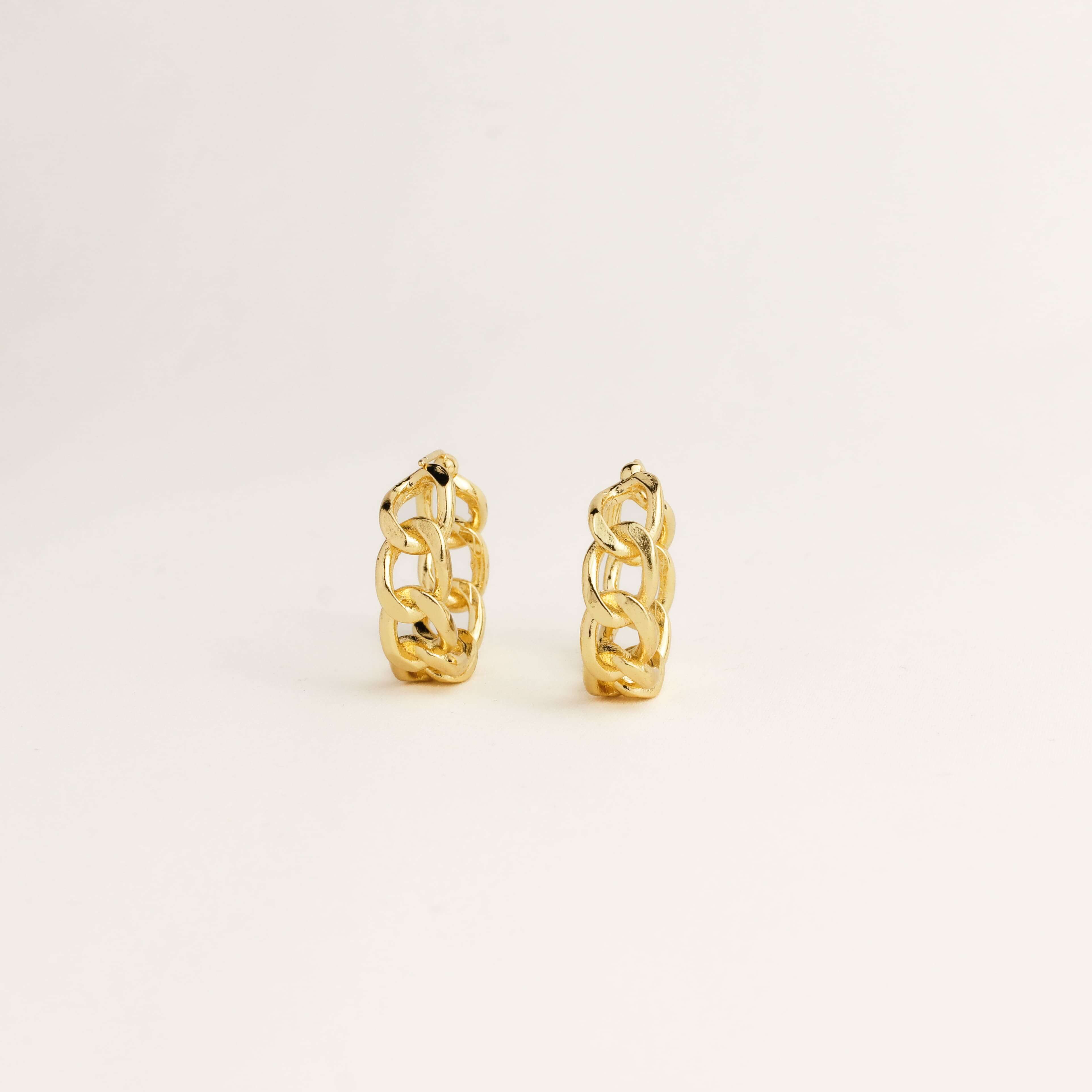 Pair of gold hoop earrings on a light beige background