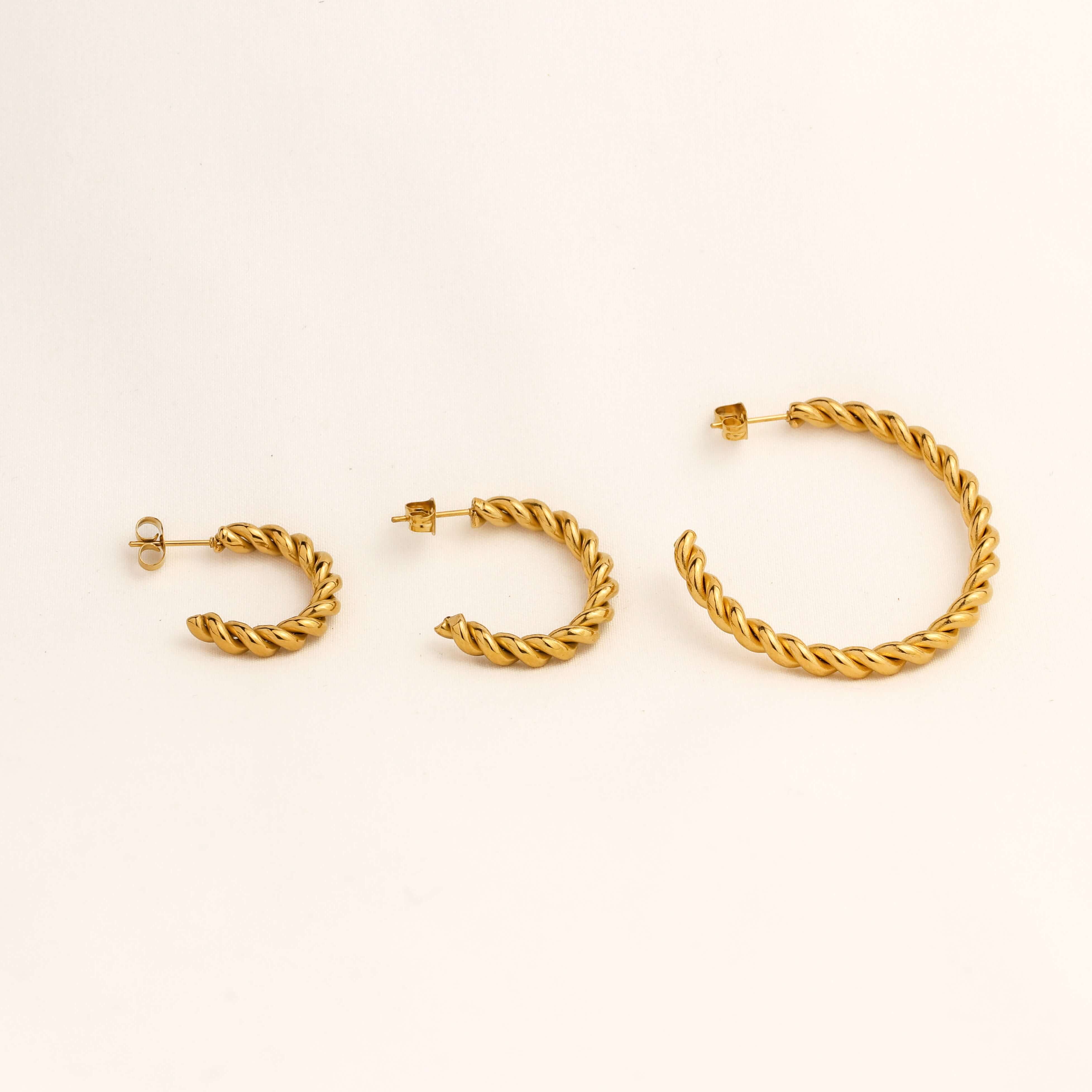 Set of gold hoop earrings on a light beige background