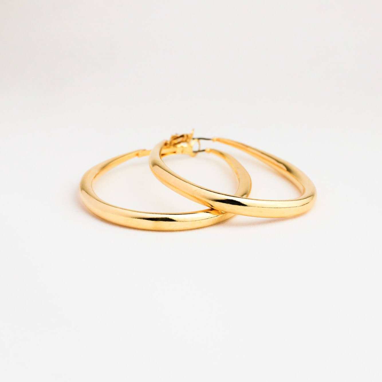 Two gold hoop earrings on a light gray background